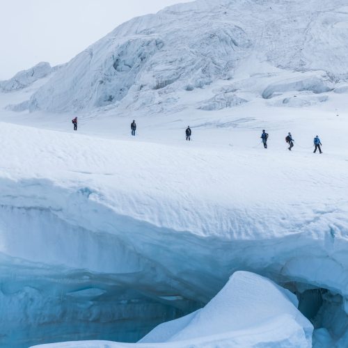 An expedition of hikers in the snowy steep mountains